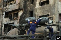 FILE - Emergency workers load debris of a warplane on a truck at the scene of a plane crash in a residential area in Yeysk, Russia, Oct. 18, 2022.
