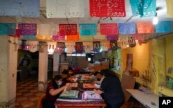 Artisans make “papel picado,” the traditional manufacture of tissue paper cutout decorations long used in altars for the Day of the Dead, in a workshop in Xochimilco, a borough of Mexico City, Oct. 27, 2022.