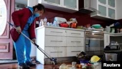 Xuan Nguyen cleans up inside a damaged home following severe flooding in the Maribyrnong suburb of Melbourne, Australia, Oct. 17, 2022. 