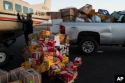 Bering Air agent Denis Sinnok shuts the door of a Cessna plane at the air strip after unloading the dozens of boxes of Eggo waffles and other goods in Shishmaref, Alaska, Thursday, Oct. 6, 2022.