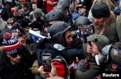 FILE - Pro-Trump protesters clash with DC police officer Michael Fanone at a rally to contest the certification of the 2020 US presidential election results at the U.S. Capitol Building, Jan. 6, 2021.