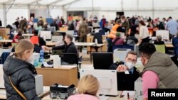 FILE - Members of the German armed forces Bundeswehr help to register refugees from Ukraine, fleeing the Russian invasion of Ukraine, inside a tent at a newly built arrival centre on the tarmac of the former Tegel airport in Berlin, March 22, 2022.