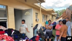 Residents of apartments in Harlem Heights, Fla., clean out clothes and other possessions from their apartments swamped by flood waters from Hurricane Ian, Oct. 1, 2022.