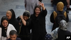 FILE - A woman flashes a victory sign as she walks around in the old main bazaar of Tehran, Oct. 1, 2022. 