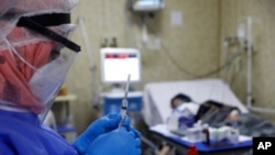 FILE - A nurse prepares a syringe for a patient infected with the coronavirus in the intensive care unit at the Syrian American Medical Society Hospital, in the city of Idlib, northwest Syria, Sept. 20, 2021.