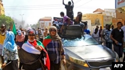 A vehicle carrying demonstrators drives alongside others marching in a protest in the area of Bashdar in the south of Khartoum, Sudan, Oct. 25, 2022, on the first anniversary of the military's arrest of the civilian administration that shared power after the 2019 overthrow of autocrat Omar al-Bashir.