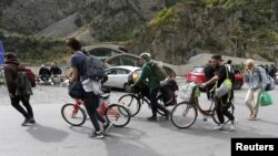 Travelers walk after crossing the border with Russia at the frontier checkpoint Verkhny Lars - Zemo Larsi, Georgia, Sept. 28, 2022.