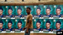 FILE - A man walks past campaign posters displayed in Osogbo, Osun State in southwest Nigeria, July 15, 2022. Fact-checkers across the country say they are joining forces to counter misinformation in the runup to the general election.