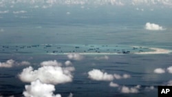 FILE - This photo taken through a window of a military plane shows Mischief Reef in the Spratly Islands in the South China Sea, May 11, 2015.