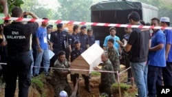 FILE - Malaysian officials provide Muslim burials to 21 human trafficking victims, believed to be Rohingya refugees, found in shallow graves in jungles bordering Thailand, in Kedah, Malaysia, June 22, 2015.