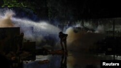 A demonstrator takes cover during an anti-government protest as lawmakers debate on constitution change, outside of the parliament in Bangkok, Thailand, Nov. 17, 2020. 