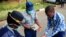 Police officers show a visitor how to disinfect his hands against the spread of coronavirus disease at State House in Harare, Zimbabwe, March 19, 2020.