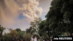 People attend a wedding ceremony as Taal Volcano sends out a column of ash in the background in Alfonso, Cavite, Philippines, January 12, 2020.