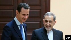 FILE - In this photo released by the Syrian official news agency SANA, Syrian president Bashar Assad, left, meets with Ali Akbar Velayati, an adviser to Iran's Supreme Leader Ayatollah Ali Khamenei, in Damascus, April 12, 2018.