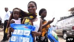 A woman carrying a baby holds a treated mosquito net during a malaria prevention action in Nigeria, April 21, 2016. WHO is providing anti-malaria drugs to children in northeast Nigeria in an effort to combat the disease.