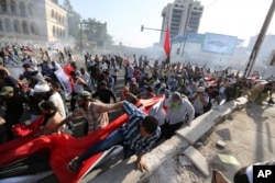 FILE - Protesters calling for government reforms run from tear gas fired by Iraqi security forces to disperse the crowd in central Baghdad, Iraq, May 27, 2016.