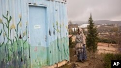 A Jewish settler covers herself from rain in Amona, an unauthorized Israeli outpost at the West Bank, east of the Palestinian town of Ramallah, Dec. 18, 2016.