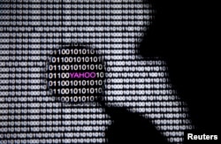 FILE - A photo illustration shows a man in front of a Yahoo logo seen through a magnifying glass in front of a displayed cyber code.