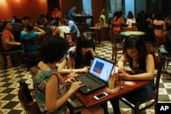 FILE - Three young Vietnamese girls go online at a cafe in Hanoi, Vietnam, May 14, 2013. The country’s potential for growth, young population and good Internet infrastructure have made it an attractive destination for regional and international investors