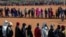 FILE - People affected by the coronavirus economic downturn line up to receive food aid in Pretoria, South Africa, May 20, 2020.