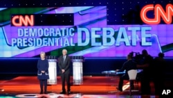 Democratic presidential candidates Hillary Clinton, left, and Sen. Bernie Sanders, I-Vt., take the stage before a Democratic presidential primary debate at the University of Michigan-Flint, Sunday, March 6, 2016, in Flint, Michigan.