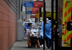 Medical workers move a patient between ambulances outside the Royal London Hospital amid the spread of the coronavirus disease pandemic, London, Jan. 27, 2021.