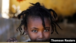 FILE - An Ethiopian girl stands at the window of a temporary shelter at the Village 8 refugees transit camp, which houses Ethiopian refugees fleeing the fighting in the Tigray region, near the Sudan-Ethiopia border, Sudan, Dec. 2, 2020.