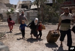 FILE - A girl ducks as she flees with her brothers in the al-Rifai neighborhood as Iraqi special forces battle Islamic State militants in western Mosul, Iraq, May 17, 2017.