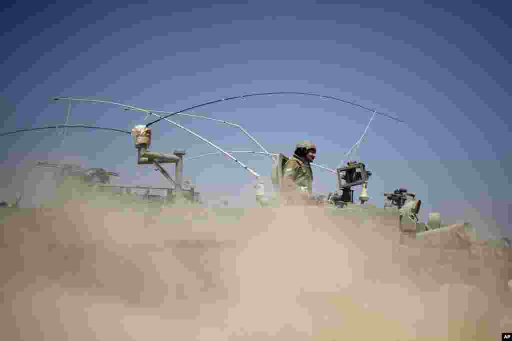 Israeli soldiers drive on an armored personal carrier near the Israel and Gaza Strip border, July 7, 2014. 