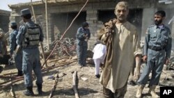 Police officers inspect the site of a suicide car bomb attack as a survivor leaves the scene, in Helmand province, Afghanistan, September 27, 2011.