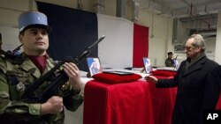 French Defense Minister Gerard Longuet (R) stands in front of the four coffins of French soldiers to pays his respects during a ceremony at Kabul Airport in Kabul on January 21, 2012.