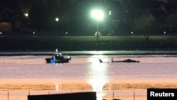 FILE - Rescuers are seen next to the wreckage of a Black Hawk helicopter that crashed into the Potomac River after colliding with an American Airlines jet near Ronald Reagan National Airport outside Washington, Jan. 30, 2025. 