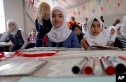 FILE - Syrian refugees pose for a photo during a visit by U.N. Secretary General Antonio Guterres to a fourth-grade classroom at the U.N.-run Zaatari camp for Syrian refugees, in northern Jordan, March 28, 2017.