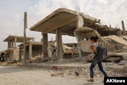Syrian children walk past debris while heading to school on the second day of the new school year on Oct. 6, 2015 in the Syrian Kurdish town of Kobani.