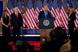 President Donald Trump speaks in the East Room of the White House, Nov. 4, 2020, in Washington, as Vice President Mike Pence and his wife Karen and First Lady Melania Trump listen.