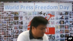 FILE - A Thai journalist walks past a banner before the International World Press Freedom Day a press conference in Bangkok, Thailand, May 3, 2017. 