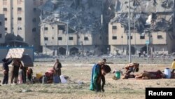 Warga Palestina membawa barang-barang mereka setelah Israel menyerang bangunan tempat tinggal di Kota Hamad yang didanai Qatar di Khan Younis. (Foto: Reuters)