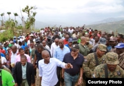 Haitian President Jovenel Moise, in white shirt, and Prime Minister Jack Guy Lafontant, in baseball cap, visited Jérémie, promising houses for people left homeless by a hurricane, March 31, 2017. (B. Magloire / VOA)