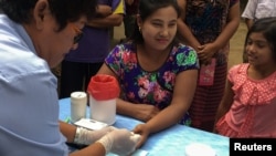 FILE - A public health worker takes a blood sample from a woman to be tested for malaria in Bo Rai district, Trat provice, Thailand.