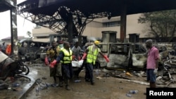 Rescue workers carry a body from the remains of a fuel station that exploded overnight in Accra, Ghana, June 4, 2015. 