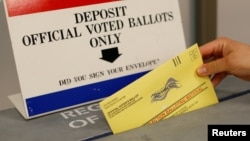 FILE - An election worker drops a ballot into a ballot box at the Registrar of Voters office in San Diego, California, U.S., June 5, 2018.