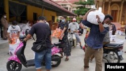FILE PHOTO - People carry sacks of rice and other food donated by the local government inside a red zone with strict lockdown measures during the latest outbreak of the coronavirus disease (COVID-19) in Phnom Penh, Cambodia, April 30, 2021. REUTERS/Cindy Liu
