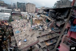 FILE - Kenyan police officers and Kenyan National Youth Servicemen search the site of a building collapse in Nairobi, Kenya, April 30, 2016.