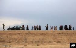 FILE - People flee their homes during fighting between Iraqi security forces and the Islamic State group during a military operation to regain control of Hit, 140 kilometers west of Baghdad, Iraq, April 13, 2016.