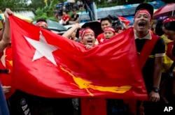 Supporters of Myanmar's National League for Democracy party brave rain outside the NLD headquarters in Yangon, Myanmar, Nov. 9, 2015.