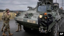FILE - Soldiers of the 2nd Cavalry Regiment stand next to a Stryker combat vehicle in Vilseck, Germany, Feb. 9, 2022.