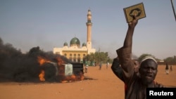 A man holds a copy of the Quran during a protest against Niger President Mahamadou Issoufou's attendance last week at a Paris rally in support of French satirical weekly Charlie Hebdo, in Niamey, Jan. 17, 2015.