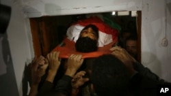 FILE - Palestinian mourners carry the body of 29-year-old activist Ibrahim Abu Thraya, who was shot and killed in clashes on the Israeli border with Gaza, during his funeral in Gaza City, Dec. 16, 2017.