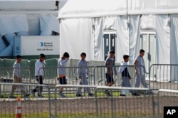 FILE - Children line up to enter a tent at the Homestead Temporary Shelter for Unaccompanied Children in Homestead, Fla., Feb. 19, 2019. A court filing Friday revealed conditions inside the facility that has become the nation’s biggest for detaining immigrant children.