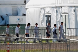 FILE - Children line up to enter a tent at the Homestead Temporary Shelter for Unaccompanied Children in Homestead, Fla., Feb. 19, 2019.